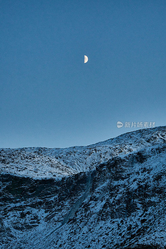 The moon rises over Godøy mountain in Møre og Romsdal, Somøre, Norway, during winter.